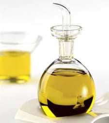Glass flask filled with yellow liquid pouring into a beaker on a white surface.