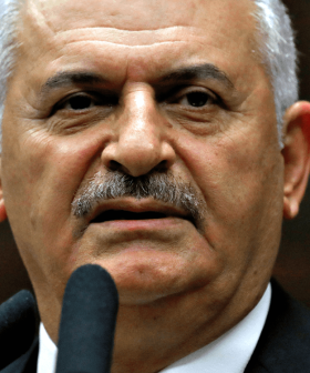 A Turkish politician speaking at a podium with a microphone, Turkish flag in the background. - Olive Oil Times