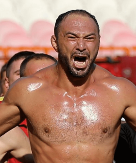 Group of enthusiastic fans celebrating at a sports event with one man prominently shouting. - Olive Oil Times