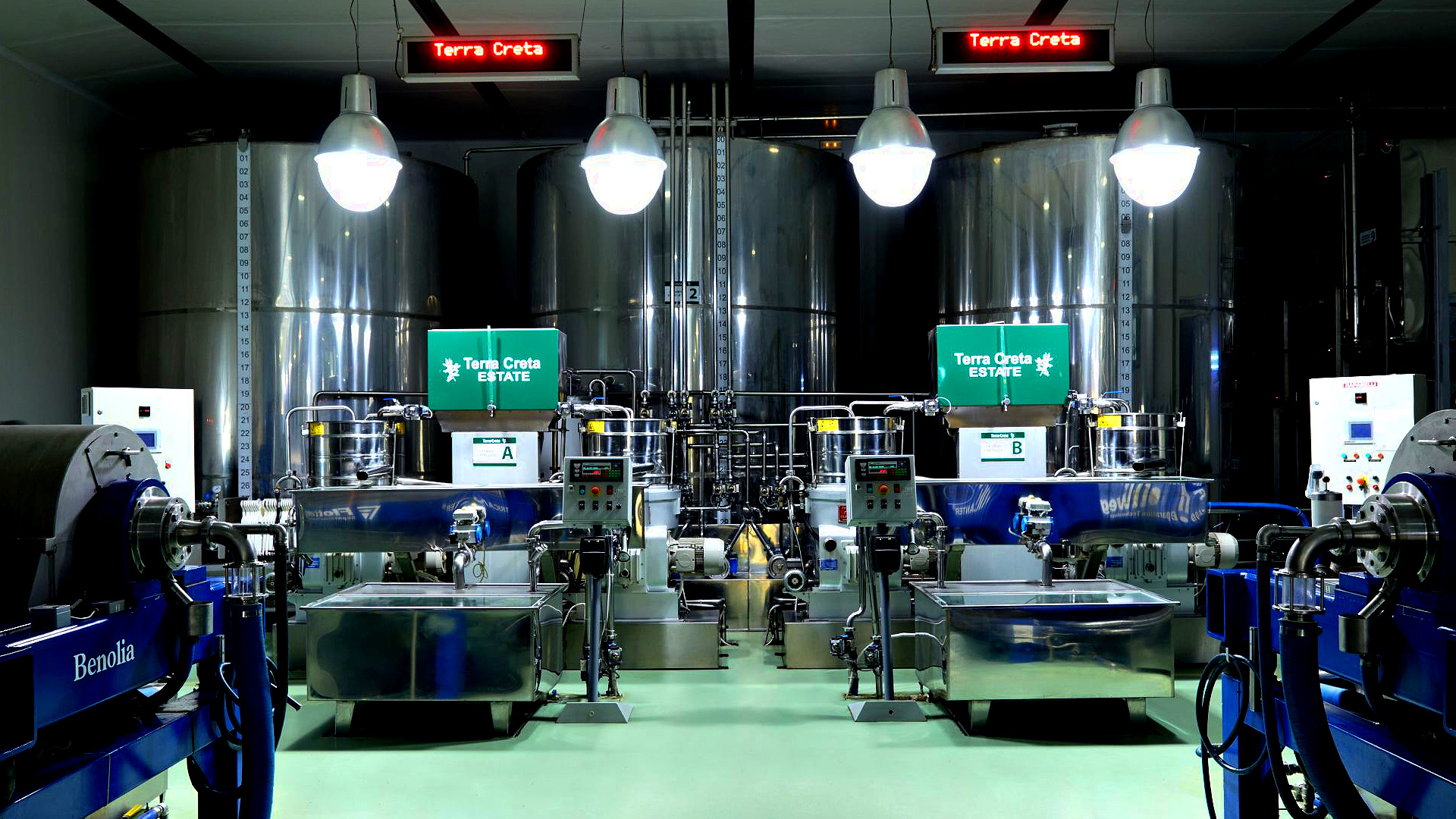 Industrial processing area featuring large stainless steel tanks and machinery with illuminated signs for "Terra Creta."