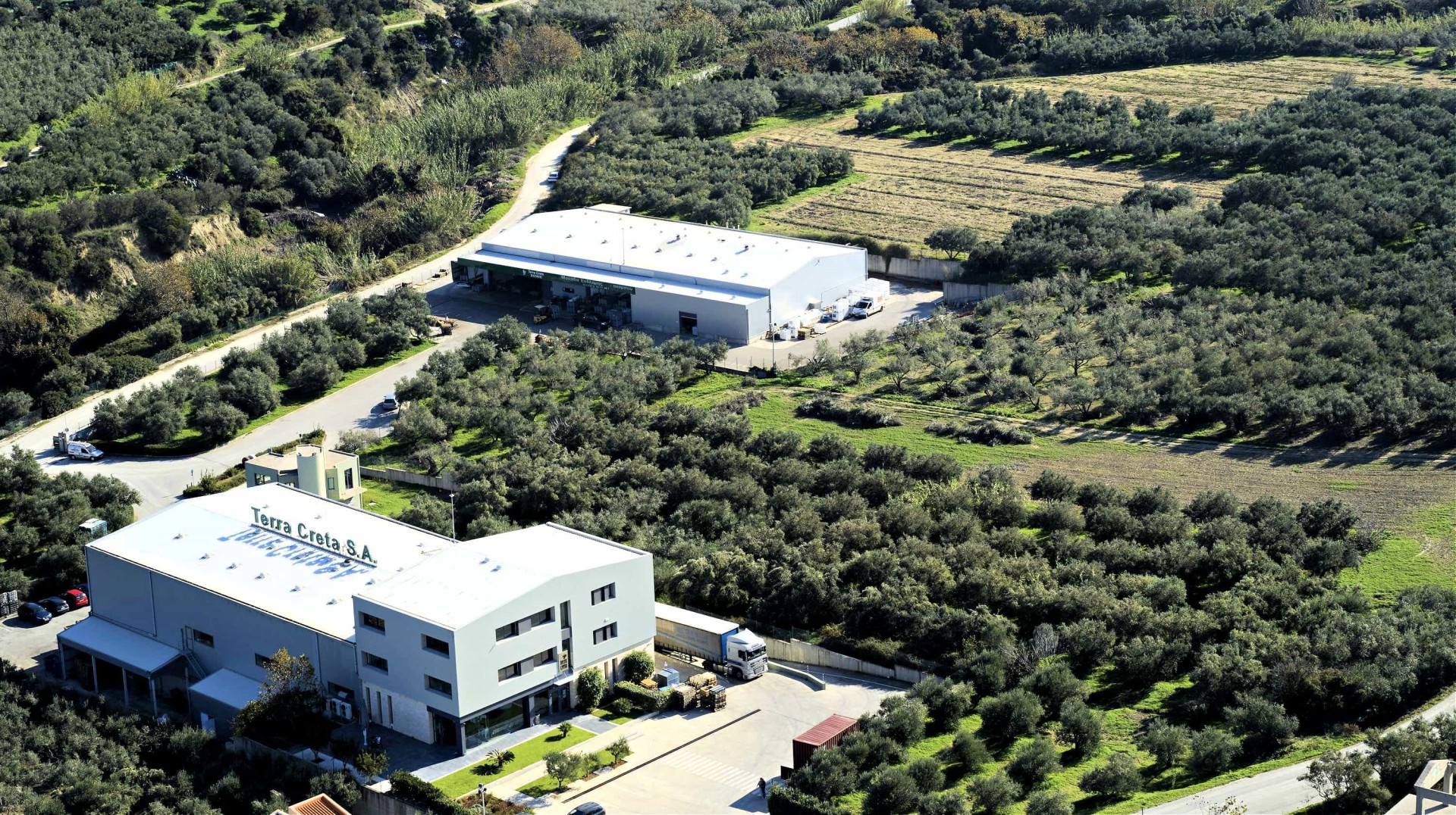 Aerial view of an olive oil production facility surrounded by olive groves and farmland.