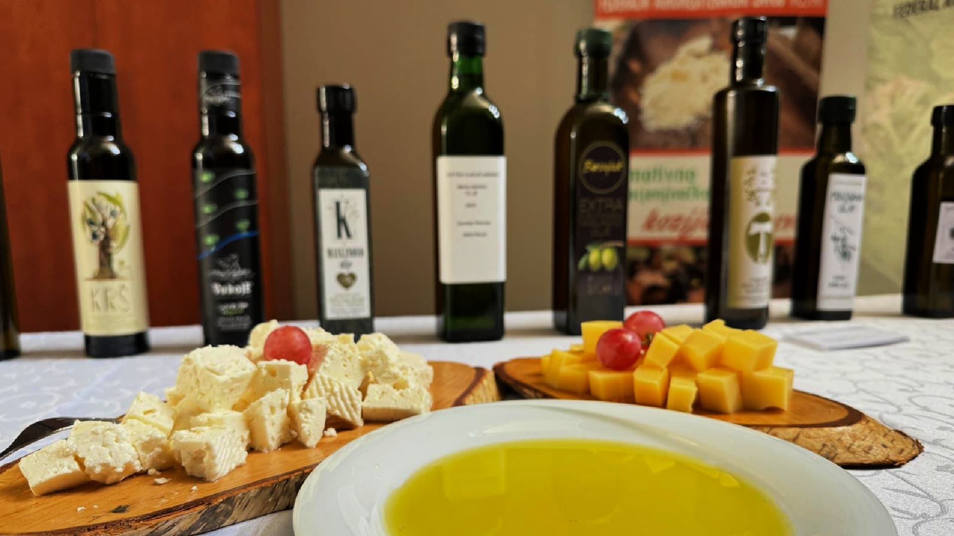 A selection of cheeses, olives, and olive oil bottles arranged on a table.