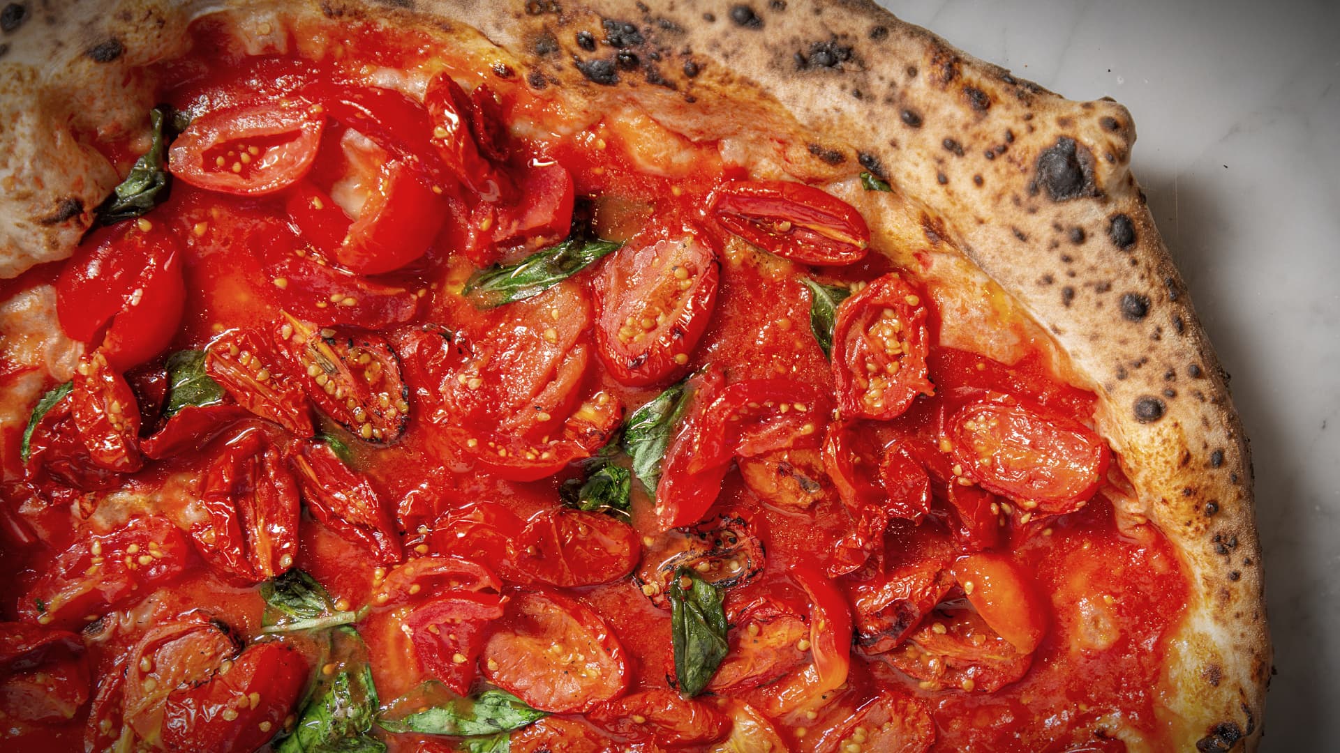 A close-up of a pizza topped with fresh tomatoes and basil on a crispy crust.