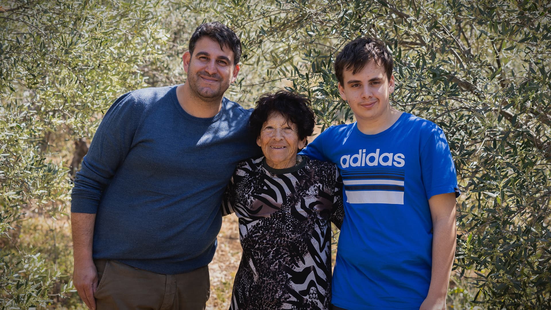 Christoforou ailesinin üç nesli — Charis, annesi Maria ve oğlu Angelos — on yıllardır Kıbrıs’taki aile çiftliğini ayakta tutan zeytin ağaçlarının arasında duruyor.